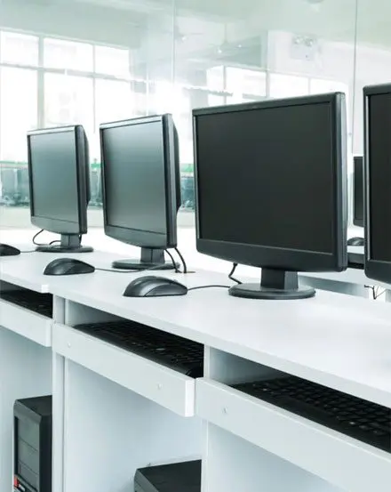 A row of computers on top of a desk.